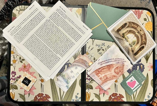 September&rsquo;s letter laid out on a floral tray: the letter pages in Zuzu&rsquo;s script, sage green envelopes edged in gold, an original print of a sunlit stone archway, a quote card that doubles as a bookmark, and the cards carrying the playlist code.