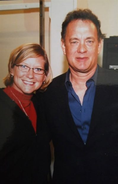 Susannah standing with Tom Hanks backstage, both smiling at the camera.