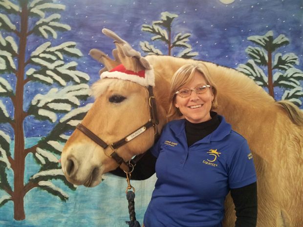 Susannah cheek to cheek with Saunder, a Fjord horse, in front of a painted backdrop.